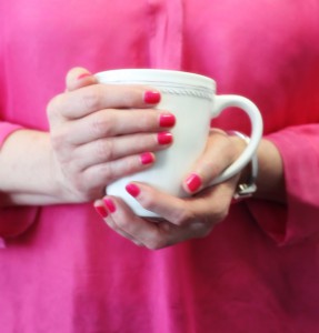 Rot lackierte Fingernägel und Hände mit Kaffeetasse.