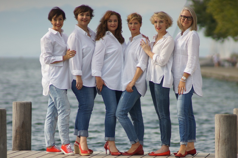 6 Frauen in weißen Blusen, Jeans und roten Schuhen.
