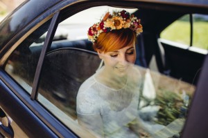 Braut im Auto mit Blumenkranz.